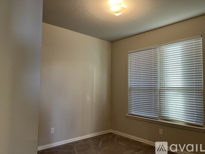 A room with a window covered by white blinds.