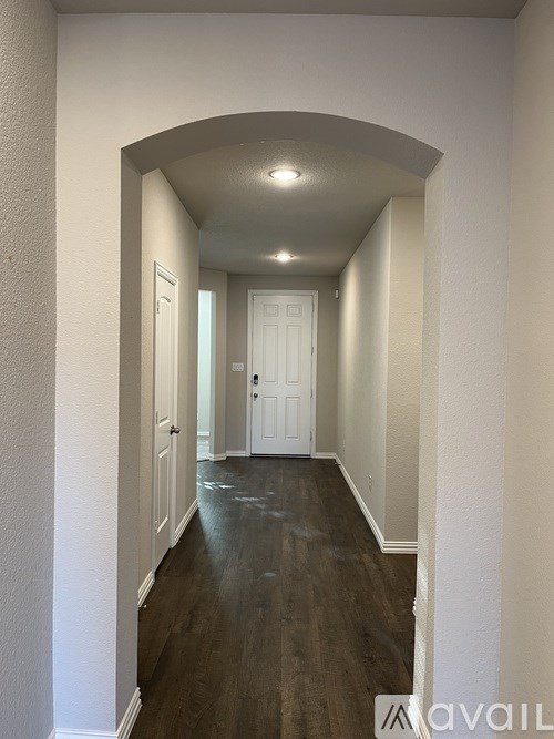 A long hallway with white walls and wood flooring.