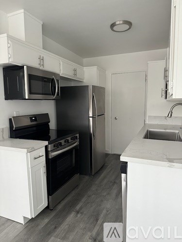 A kitchen with white cabinets and a black fridge.