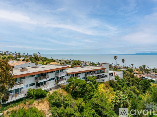 A large white building with a balcony overlooks a body of water.