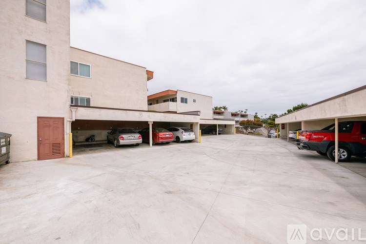 A parking lot with a few cars and a building in the background.