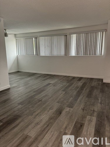 A room with wooden flooring and two windows.