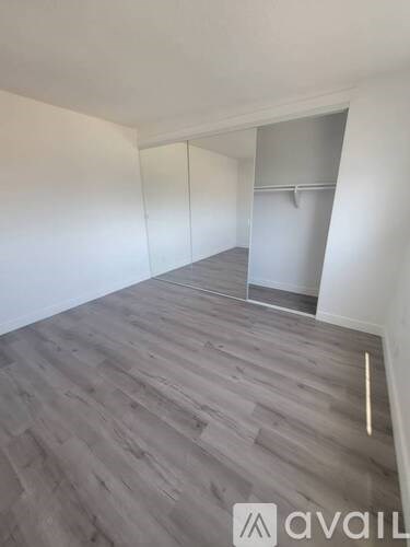 A room with grey wooden flooring and white walls.