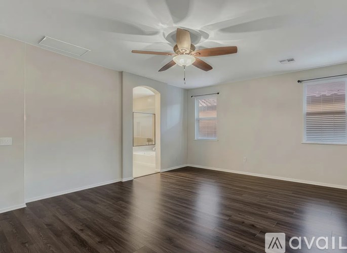 A room with a ceiling fan and wooden flooring.