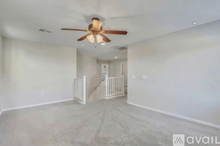 A spacious room with a ceiling fan and a staircase.
