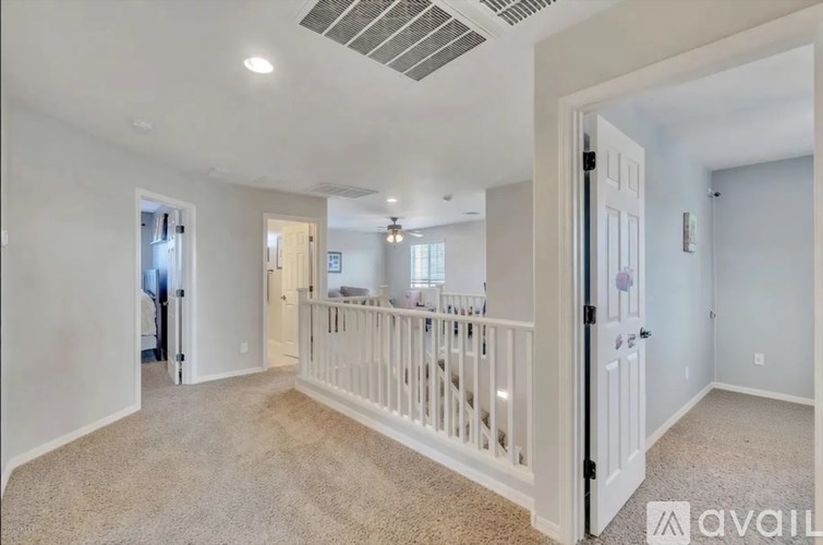 A spacious room with a carpeted floor and a ceiling fan.