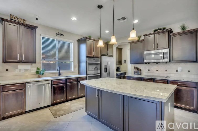 A kitchen with a marble countertop and dark wood cabinets.