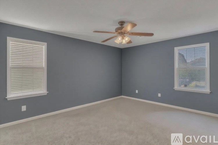 A room with a ceiling fan and two windows.