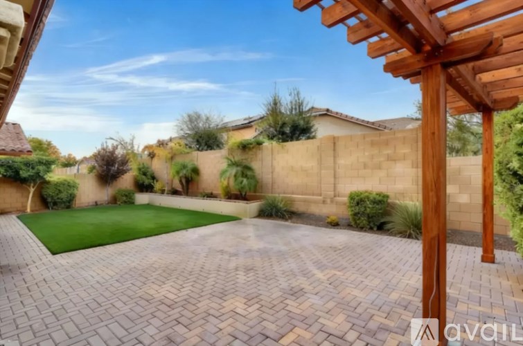 A backyard with a wooden pergola and a brick patio.