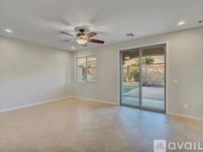 A spacious room with a ceiling fan and sliding glass doors leading to a patio.