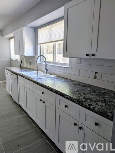 A kitchen with white cabinets and a granite countertop.