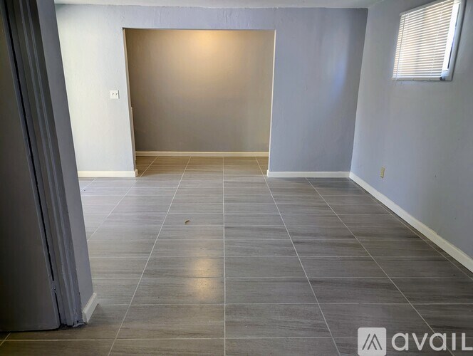 A room with grey tiled flooring and a white wall.