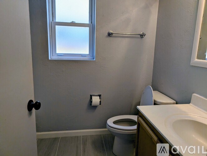 A bathroom with a toilet, sink, and a window.