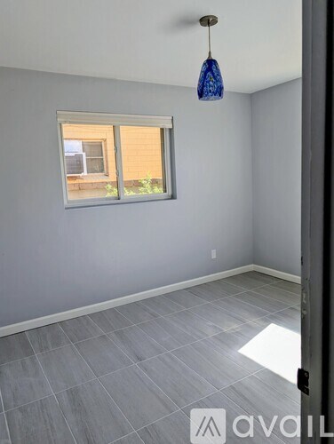 A room with a grey floor and a window with blinds.
