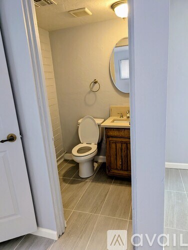 A bathroom with a toilet, sink, and mirror.