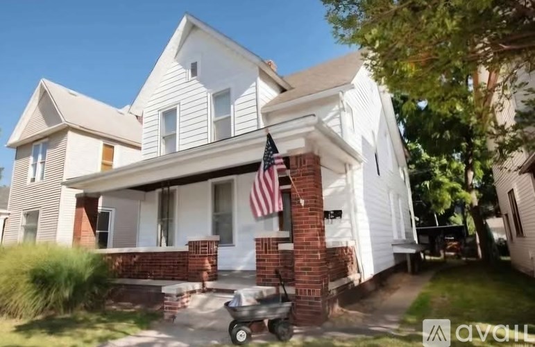 A white house with a red brick pillar and an American flag.