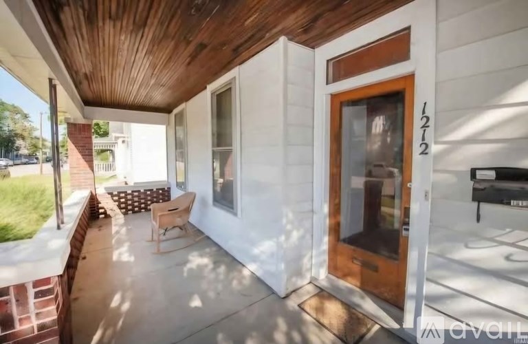 A white house with a brown door and a wooden ceiling.