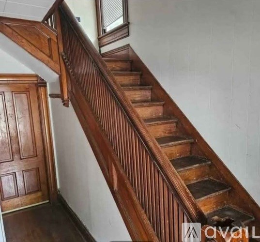 A wooden staircase with a handrail and a door on the left side.