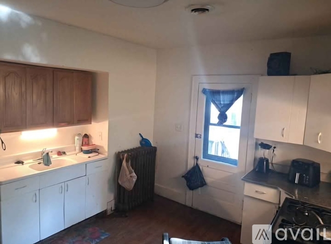 A kitchen with white cabinets and a window with a blue curtain.