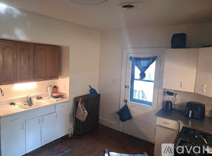 A kitchen with white cabinets and a window with a blue curtain.
