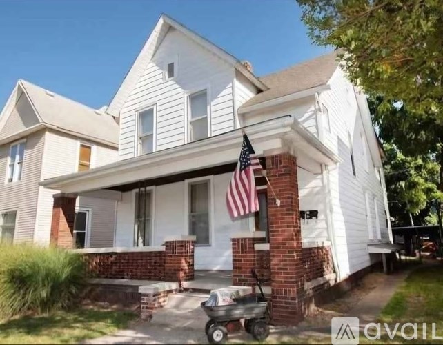 A white house with a red brick pillar and an American flag.