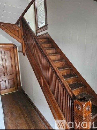 A wooden staircase with a handrail and a door at the bottom.