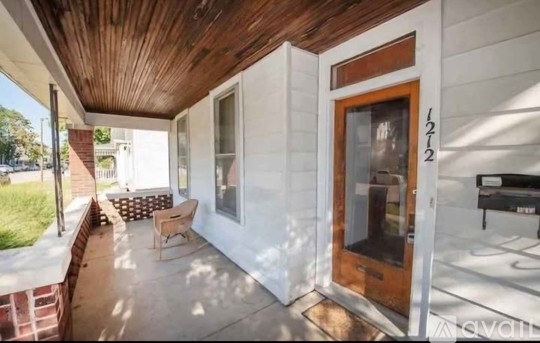 A white house with a brown door and a wooden porch.