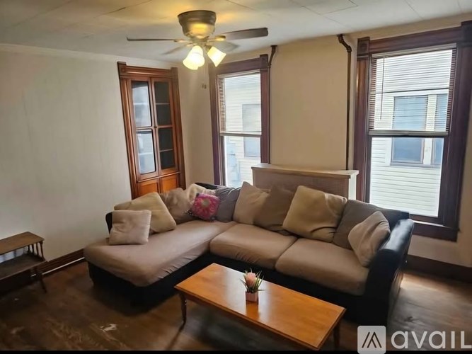A living room with a sofa, a table, and a ceiling fan.
