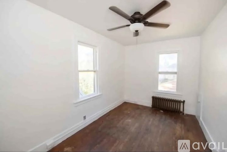 A room with a ceiling fan and two windows.