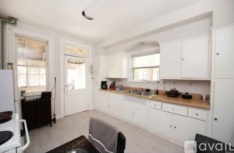 A kitchen with white cabinets and a black chair.