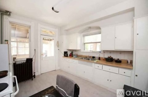 A kitchen with white cabinets and a black chair.