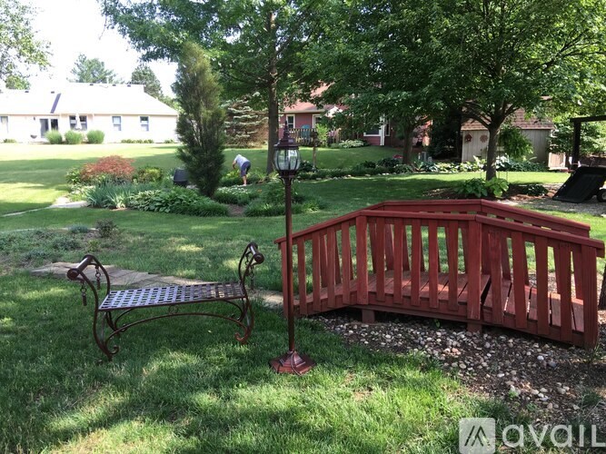 A red wooden bench with a metal frame is in the foreground of a grassy area.