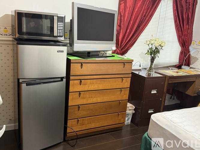 A kitchen area with a microwave, refrigerator, and a desk with a computer monitor.