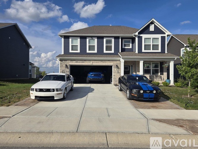 Two cars are parked in front of a two-story house.