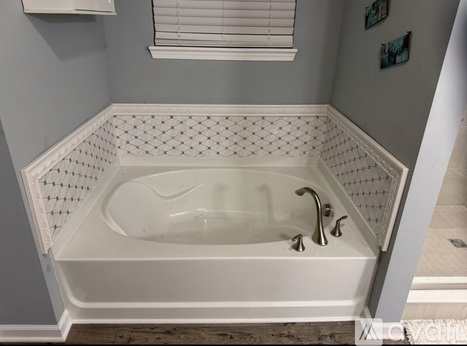 A white bathtub with a shower head and faucet.