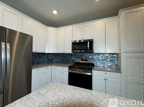 A kitchen with white cabinets and a granite countertop.