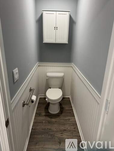 A white toilet in a small bathroom with a cabinet above it.