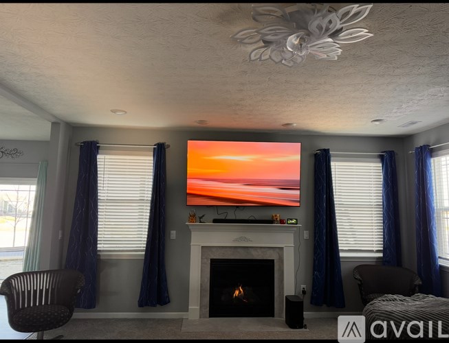 A living room with a fireplace and a flat screen TV mounted on the wall.