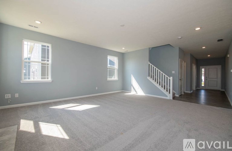 A spacious room with a staircase leading to another room.