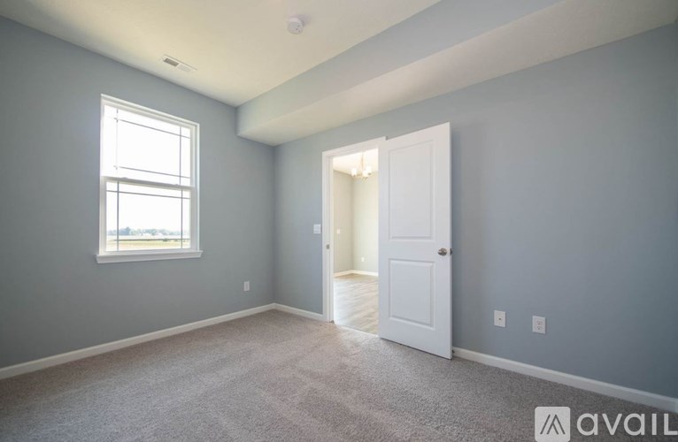 A room with a carpeted floor, a door, and a window.