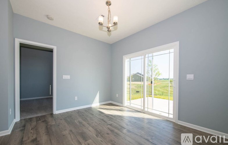 A room with a chandelier and a view of a lawn through the windows.