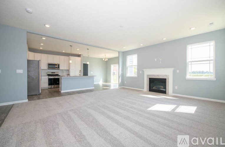 A spacious living room with a fireplace and a kitchen area in the background.