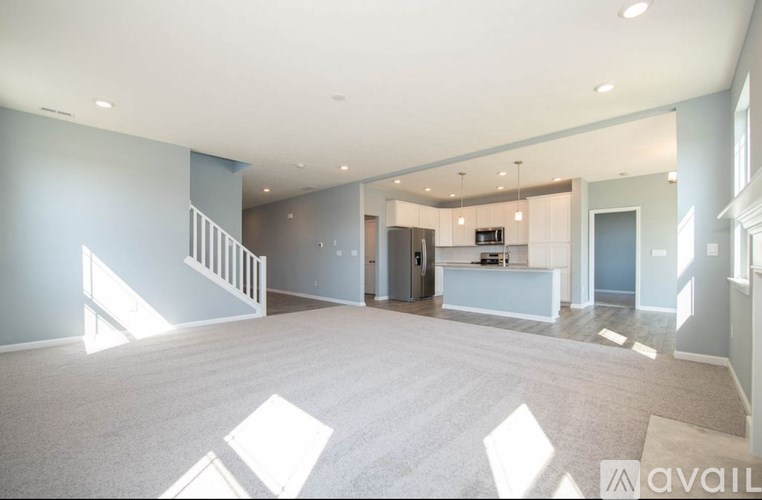 A spacious living room with a kitchen in the background.