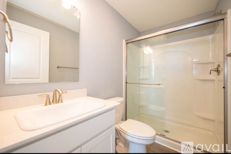 A white sink and toilet in a bathroom with a glass shower door.