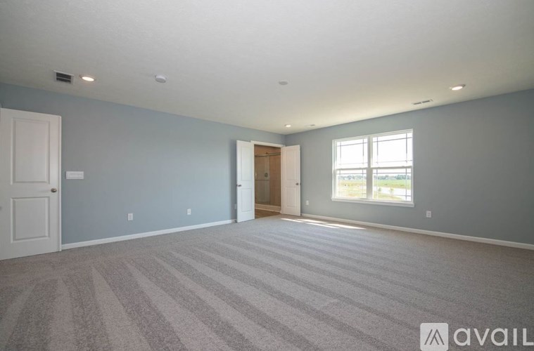 A spacious room with a carpeted floor and a large window.