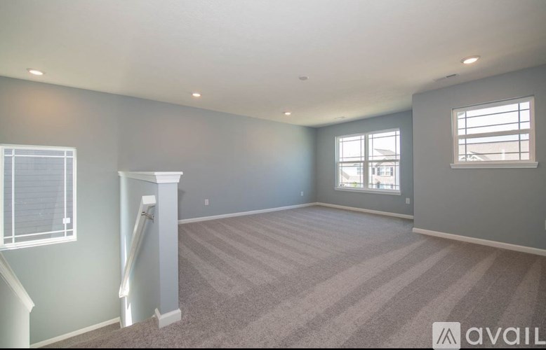 A spacious room with a carpeted floor and a window with blinds.