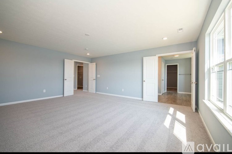A spacious room with carpeted floor and white walls.
