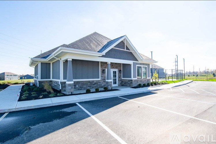 A house with a grey roof and a parking lot in front.