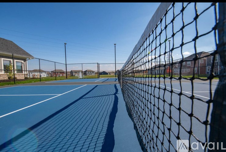 A tennis court with a black fence and a blue surface.
