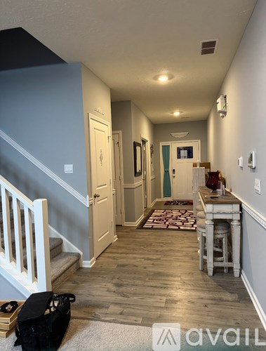 A hallway with a staircase on the left and a table with chairs on the right.